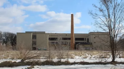 Abandoned school building with brick smokestack in winter.