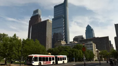 White city bus on road in Philadelphia, Pennsylvania with tall city buildings in background.