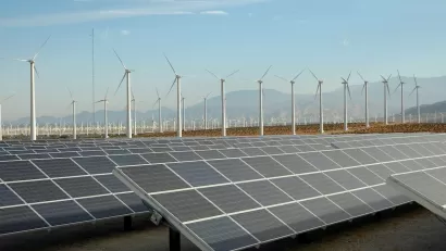 Large solar panel installation and wind turbines with Southern California desert mountains in background.