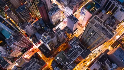 Bird's eye view of city skyscrapers at twilight with blurred lights on streets.