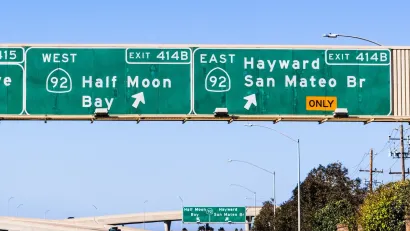 Green and white interstate freeway signs pointing to Hayward and San Mateo and Half Moon Bay exits in Northern California.