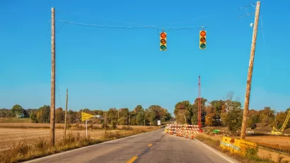 Two-lane rural road with stoplights hanging above roadway and construction visible in distance.