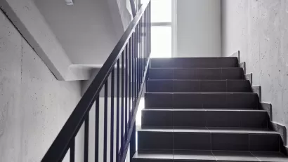 View of plain building staircase with light coming in from window on landing