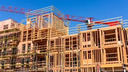 Wood-framed multi-family building under construction with red crane behind it.