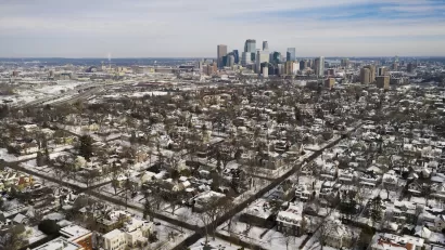 Aerial view of Minneapolis neighborhood and downtown skyline in winter with snow.