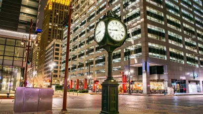 Historic clock on the corner of an intersection in downtown Houston at night.