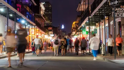 People walking down Bourbon Street in New Orleans at night.