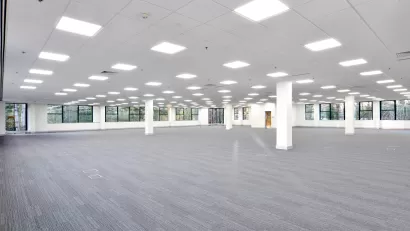 Large empty office building floor with white walls and grey carpeting