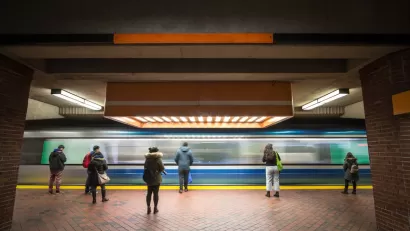People waiting on subway platform with blurred train passing by.