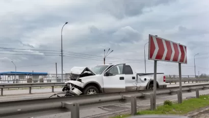 White truck with crumpled front sitting on highway after crash.