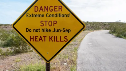 Yellow roadside sign with extreme heat warning: "Danger - Extreme Conditions! - STOP - Do not hike Jun-Sep - HEAT KILLS"