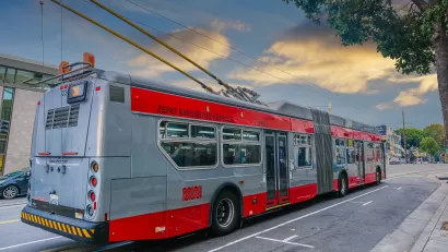 Red and silver Muni trolley bus connected to overhead wires on San Francisco street