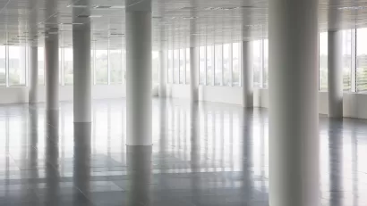 White round pillars in empty office building with windows across all walls and white floors and ceiling.