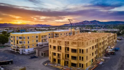 Multifamily wood-frame buildings under construction in Fork, Utah with sunset sky and mountains in background.