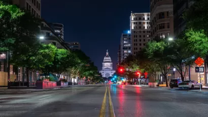 Low angle view of Texas state capitol at night from middle of wide street.