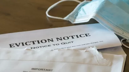 Eviction notice on table with surgical face mask lying next to it.