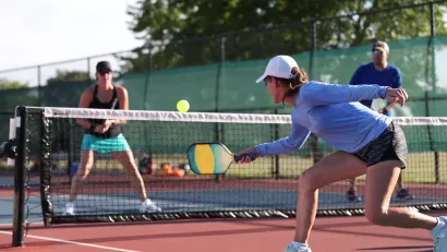 Four people playing pickleball on outdoor court