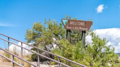 Wood WELCOME sign with Bureau of Land Management name and logo next to concrete stairwell outdoors in Utah.