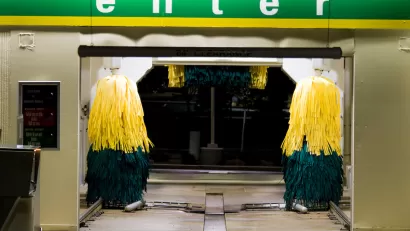 Entrance to a drive-through car wash at night with green 'Enter' sign.