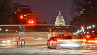 View of U.S capitol dome at night with blurred traffic in foreground