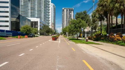 Two-way protected bike lane on wide street in downtown St. Petersburg, Florida with high-riise buildings in background.