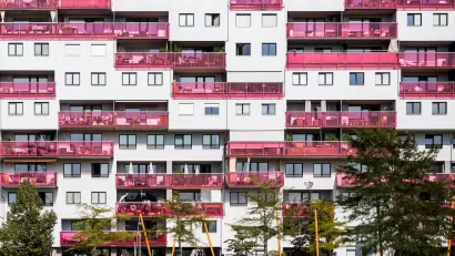 Multistory apartment building facade in Vienna, Austria with pink glass balconies.