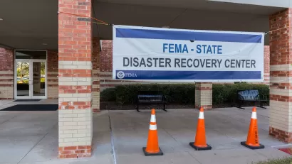 "FEMA - STATE disaster recovery center" banner on brick building.