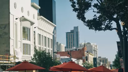 The tops of umbrellas for outdoor dining spaces are visible with large buildings in the background on a sunny day in the city of San Diego.