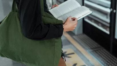 Close-up of person standing and holding book on train platform.