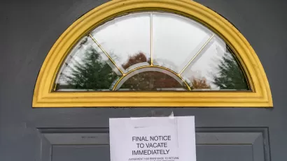 Eviction notice taped to dark grey door with arched window at top.
