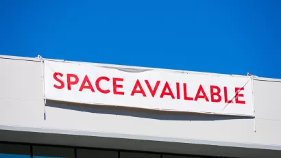 White banner with red "SPACE AVAILABLE" text hanging at top of white office building.