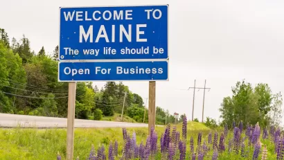 Blue "Welcome to Maine" road sign.