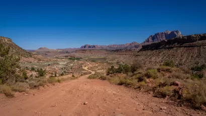 Dirt road on BLM land in Utah near Zion National Park with red cliff formations in background.