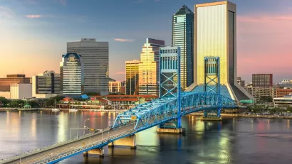 Aerial view of downtown Jacksonville, Florida skyline with bridge in foregorund at dusk.