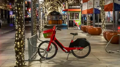Lime rental bike on sidewalk in Denver, Colorado with Christmas lights in background.