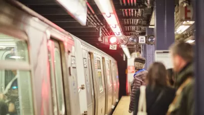 People waiting to board subway train on platform in New York City.