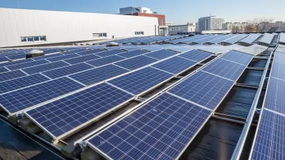 Rows of solar panels on a large rooftop with office or industrial buildings in background.
