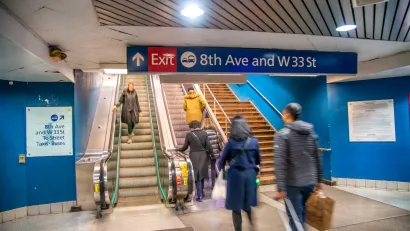 People walking up and down stairs in New York City subway station.