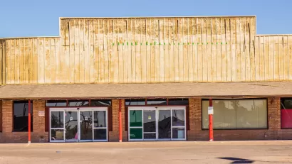 One-story vacant Western-style strip mall with blocked windows.