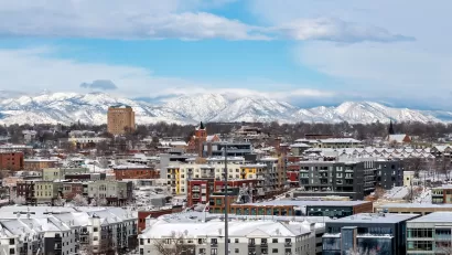 View of snowy buildings and mountains in background in Denver, Colorado.
