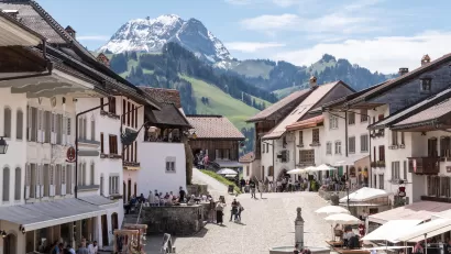 View of pedestrian plaza in Swiss village with Alps in background.