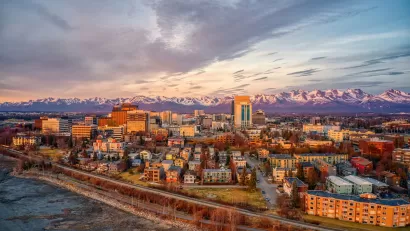 Aerial view of Anchorage, Alaska downtown with mountains in background at golden hour.