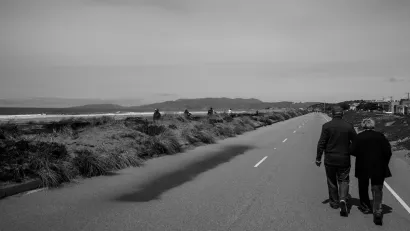 Black and white photos of couple walking on Great Highway road in San Francisco on the water during the pandemic when the road was closed to vehicular traffic.