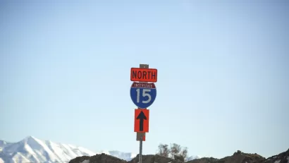 Blue and white Interstate 15 North sign against backdrop of blue sky and snow-capped mountains in Utah