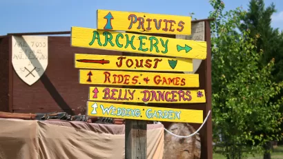 Signpost with signs for archery, jousting, privies, etc at Renaissance faire