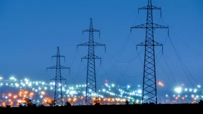 Tall power line towers with blurred city lights in background.