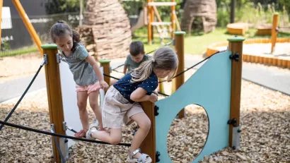 Group of three children playing on playground equipment.