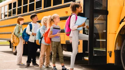 Children boarding yellow school bus.