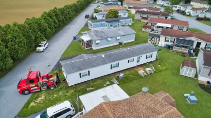 Aerial view of mobile home being moved in a mobile home park by a red truck.