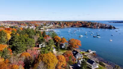 Aerial view of Maine harbor town with fall colors on trees.